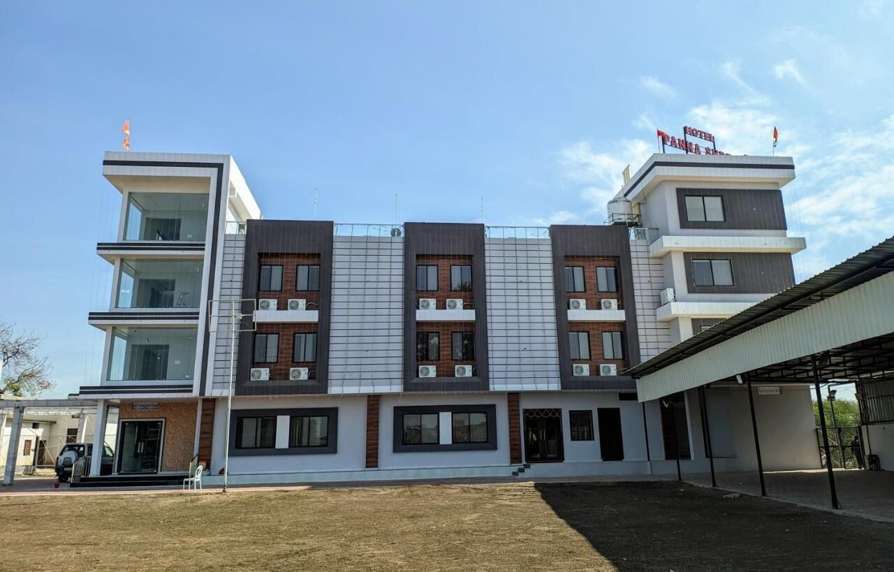 A modern hotel with a two-story structure, a covered outdoor area, and a clear sky.