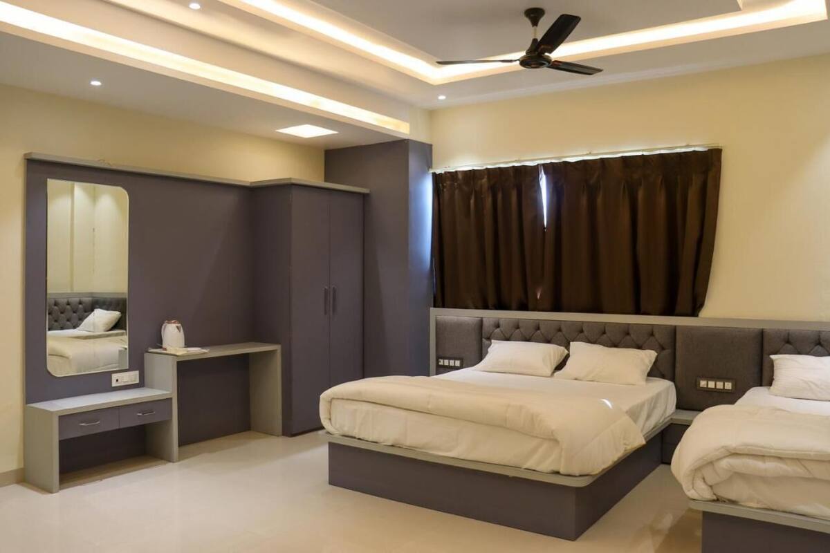 A modern bedroom with a large bed, a vanity with a mirror, and a ceiling fan.