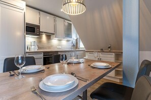 Une cuisine moderne avec une table à manger pour quatre personnes, équipée d’une machine à café, de verres à vin et d’assiettes.