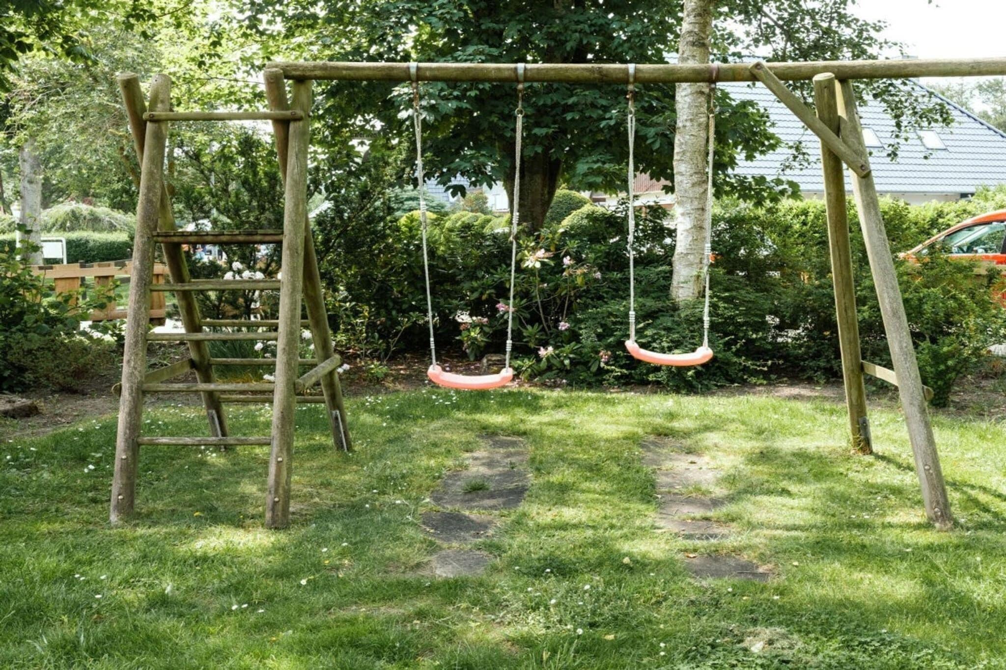 A wooden swing set in a grassy area with a ladder and dense foliage in the background.