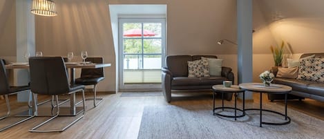 A modern living room with a dining area, a sofa set, a coffee table, and a hanging light fixture.