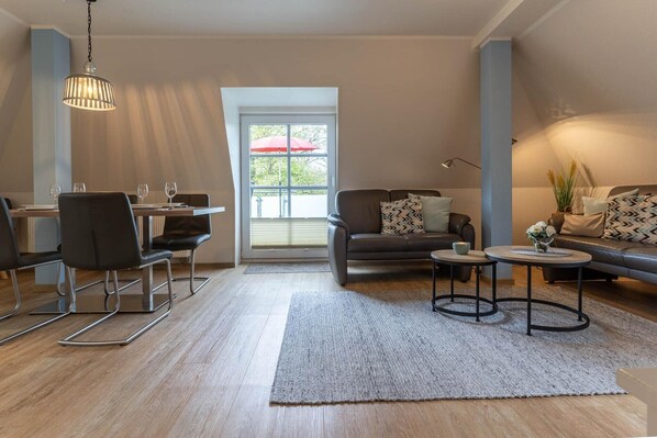 A modern living room with a dining area, a sofa set, a coffee table, and a hanging light fixture.