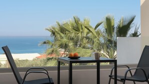 A balcony with a table, two chairs, a plate with oranges, and a glass of water.