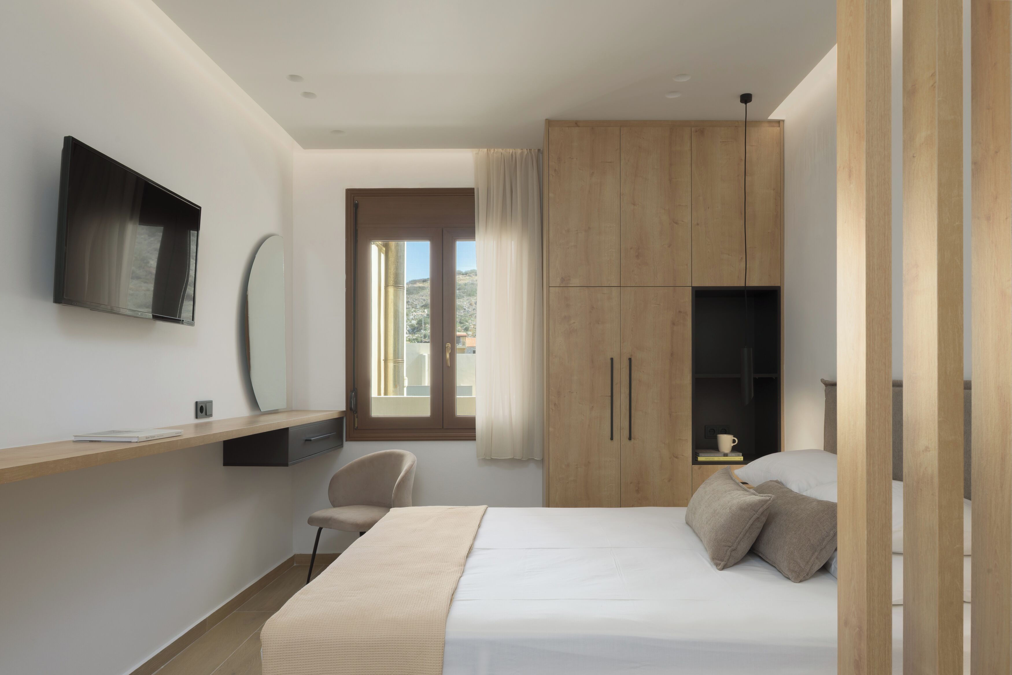 Une chambre à coucher moderne, équipée d’un lit, d’un bureau, d’une chaise et d’un téléviseur fixé au mur.