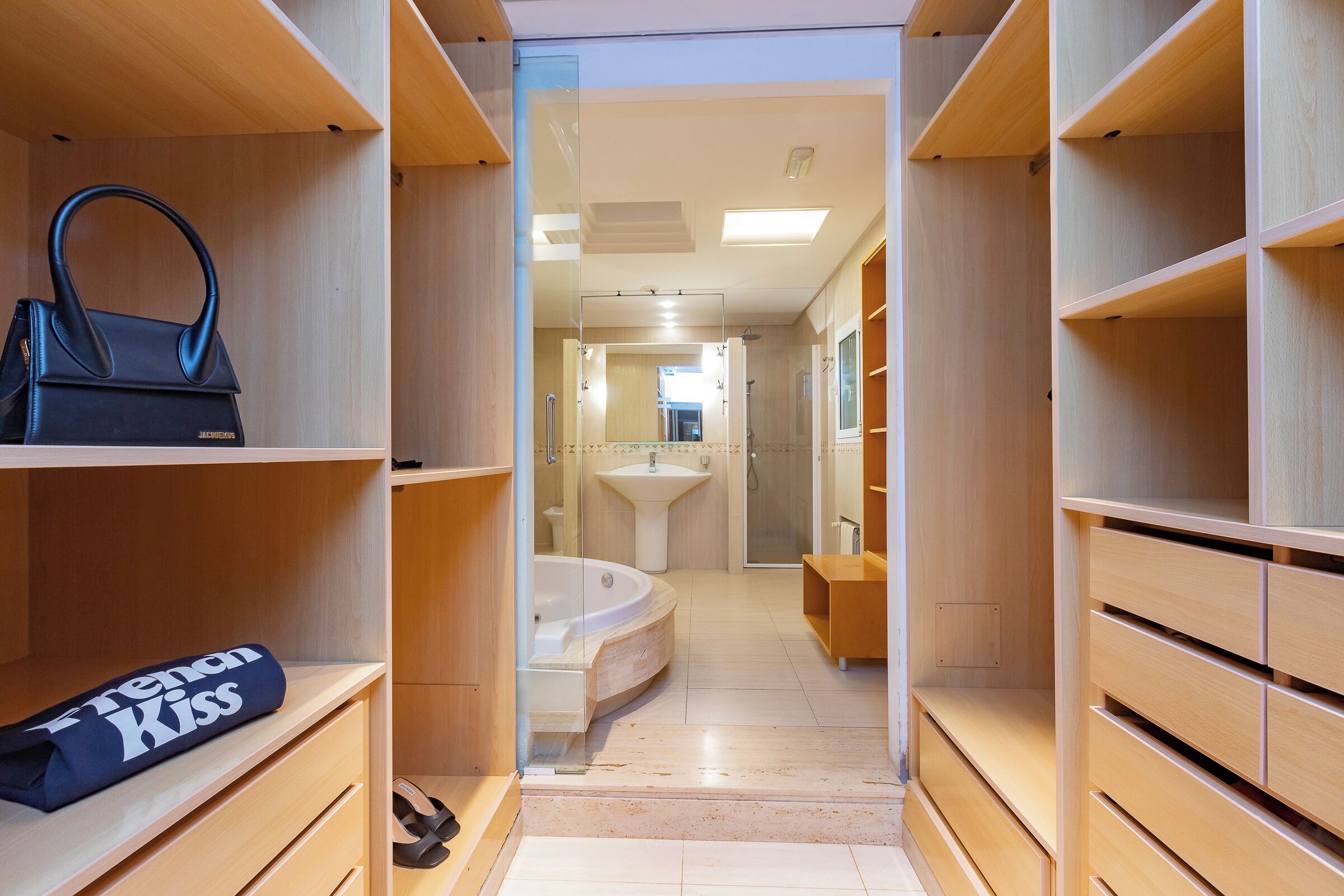 Un baño moderno con bañera, tocador y estanterías de madera.