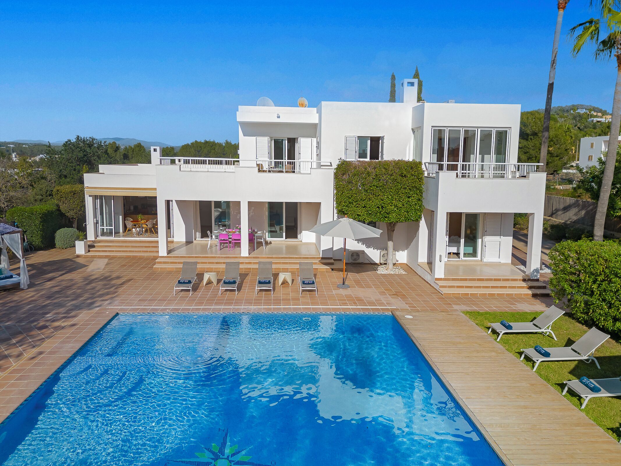 A modern two-story house with a swimming pool, outdoor seating, and a well-maintained garden.