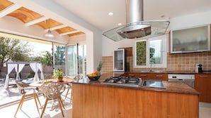 Una cocina moderna con una isla central, electrodomésticos de acero inoxidable y un amplio ventanal con vistas a un jardín.