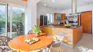 Una cocina moderna con una isla central, armarios de madera y una zona de comedor con una mesa dispuesta para dos personas.