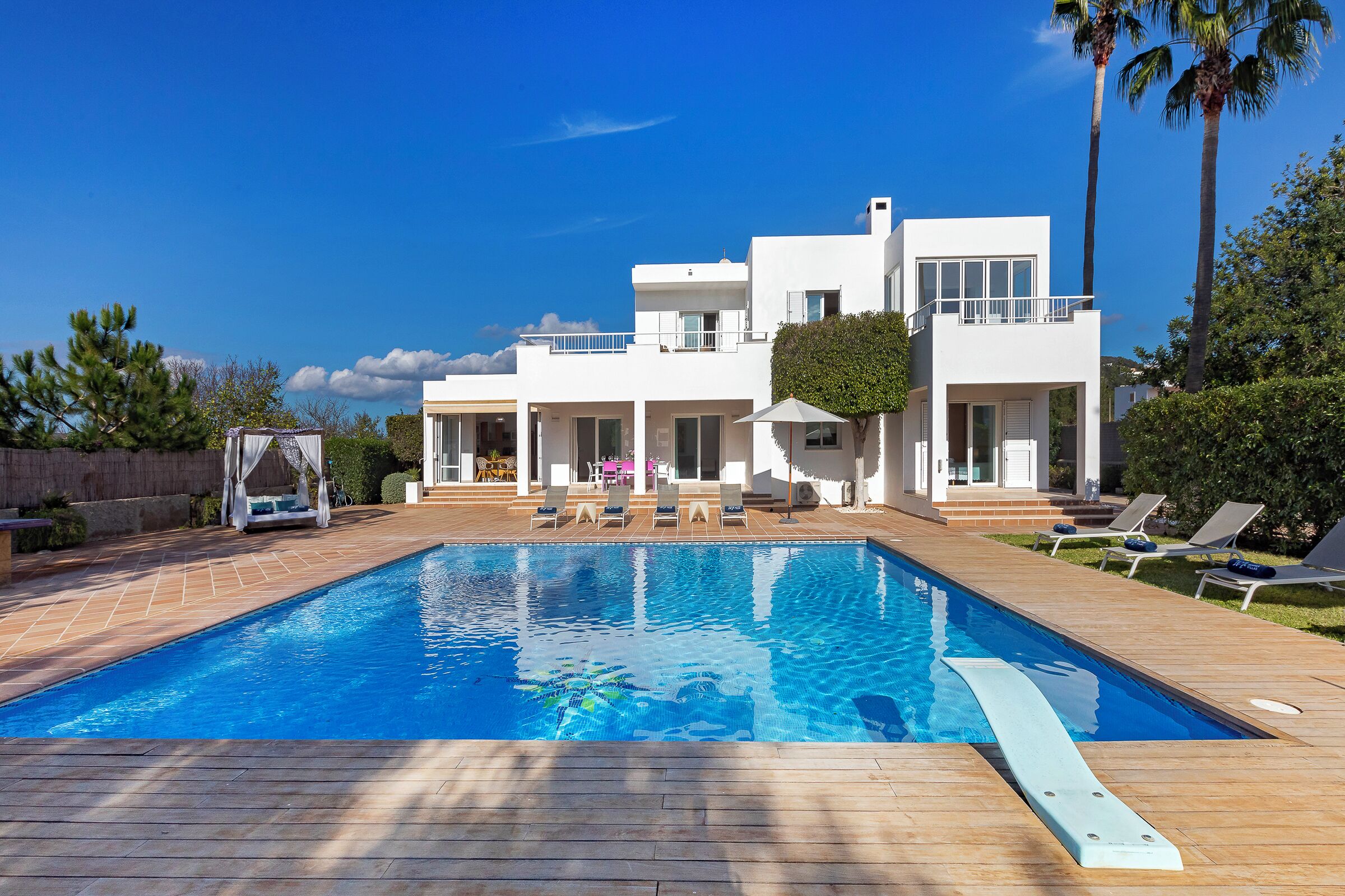 Une maison moderne dotée d’une piscine, de chaises longues et d’une terrasse en bois.