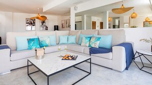 Een moderne woonkamer met een witte bank, blauwe kussens en een marmeren salontafel.
