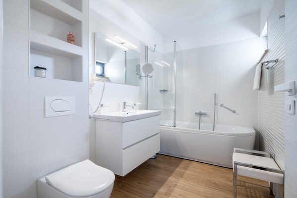 A modern bathroom with a white sink, mirror, and toilet.