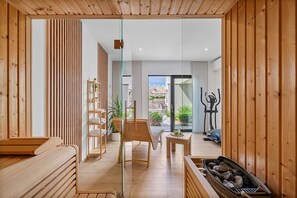 A modern interior with a wooden floor, a glass door leading to a balcony, a wooden bench, a table with a glass, and a fireplace.
