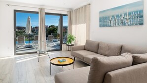 A modern living room with a beige sofa, a glass coffee table, and a view of a pool and outdoor chairs through large sliding glass doors. - Villa Consido, a 3-Bedroom Retreat with sea views (Seget Vranjica)
