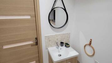 A bathroom with a wooden door, a white sink with a mirror, and a wooden ring on the wall.