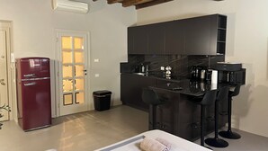 A compact kitchen with dark cabinets, a red refrigerator, and a bar area with stools. - Maison Chic Two, a stone's throw from the Spanish Steps (Roma)