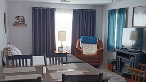 A living room with a dining table, chairs, a sofa, a TV, and curtains. - Charming 3 room apartment with WiFi , AC in lovely Aurora.  (Aurora)