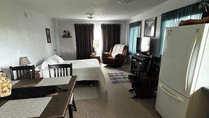 A compact living space with a bed, a dining table with chairs, a sofa, a TV, and a refrigerator. - Charming 3 room apartment with WiFi , AC in lovely Aurora.  (Aurora)