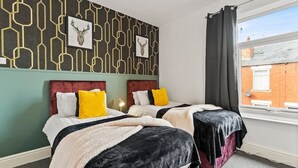 A hotel room with two beds, a geometric patterned wall, and a window with a view of a brick building. - 20% off! Boutique Doncaster Abode - Sleeps 6! (Doncaster)