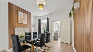 A dining area with a black table and chairs, wooden paneling on the walls, and a ceiling light fixture. - 20% off! Boutique Doncaster Abode - Sleeps 6! (Doncaster)