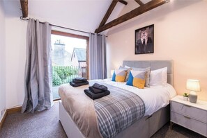 Une chambre à coucher avec un lit, une table de chevet et une fenêtre avec des rideaux.