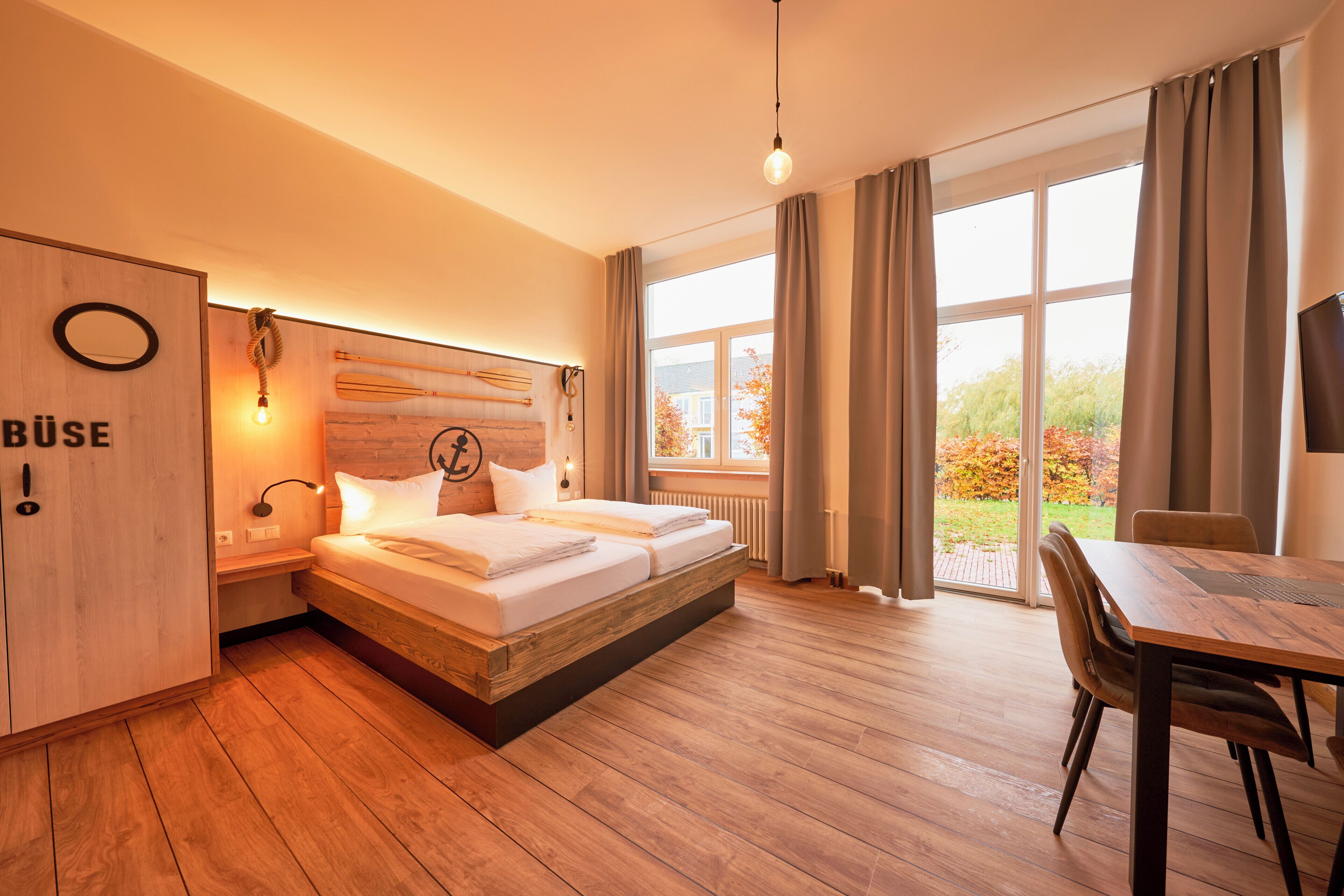 Ein Hotelzimmer mit Holzboden, einem Bett mit Kopfteil, einem Schreibtisch und einem Stuhl.