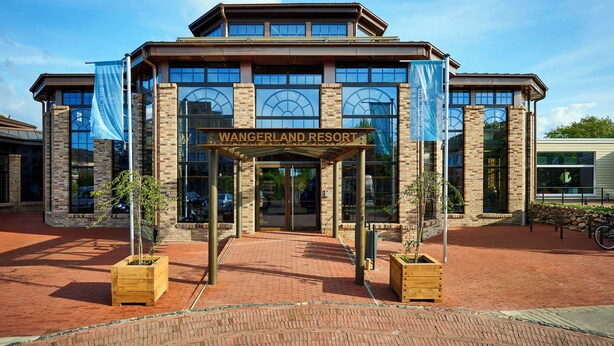 A brick building with a sign reading "Wangerland Resort" and large windows. - WANGERLAND RESORT (Wangerland)