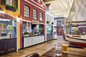 Interior de un restaurante con mostrador de madera, un modelo de barco y un vaso de jugo de naranja sobre la mesa.