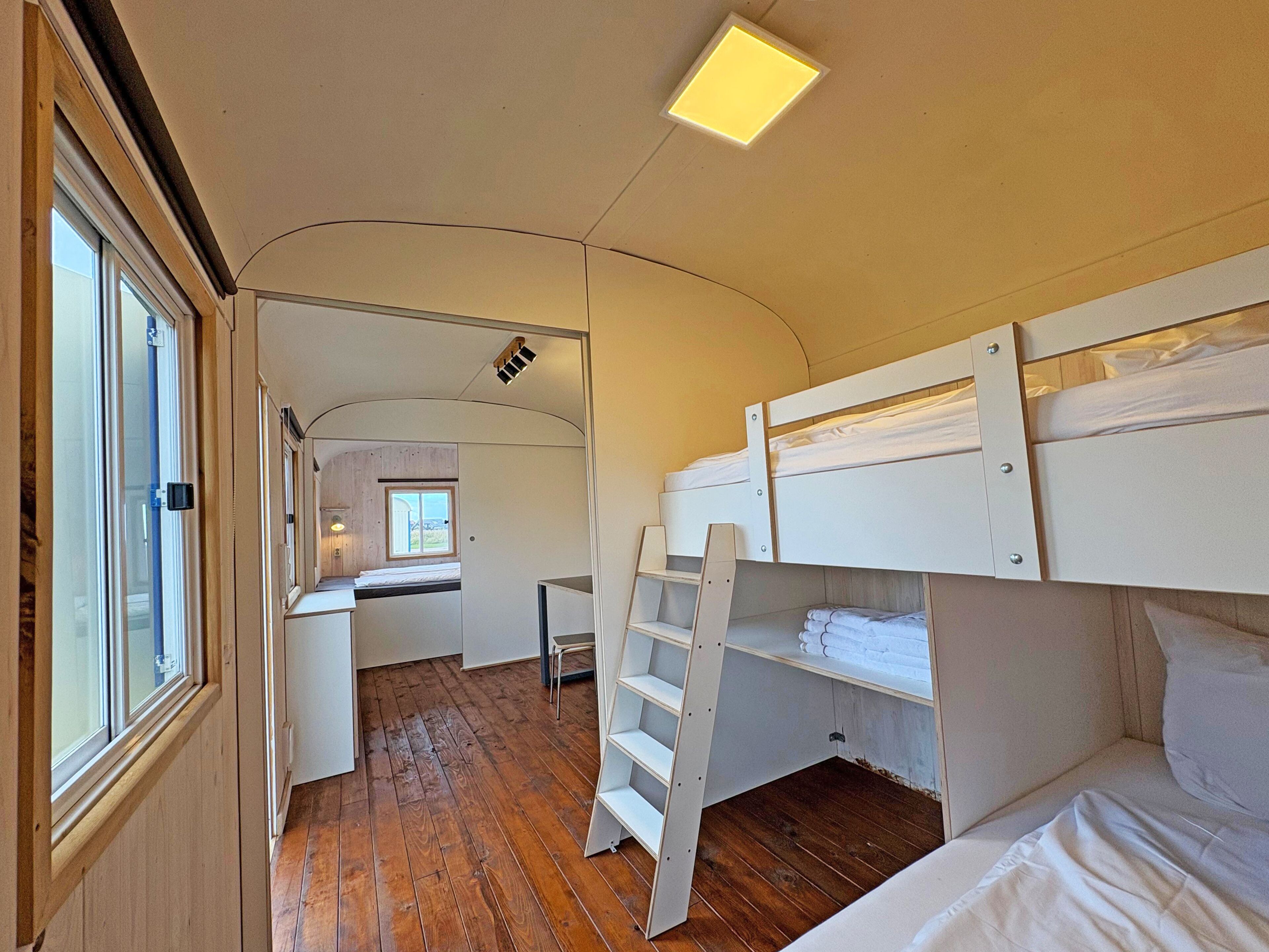 A compact room with bunk beds, a desk, and a window.