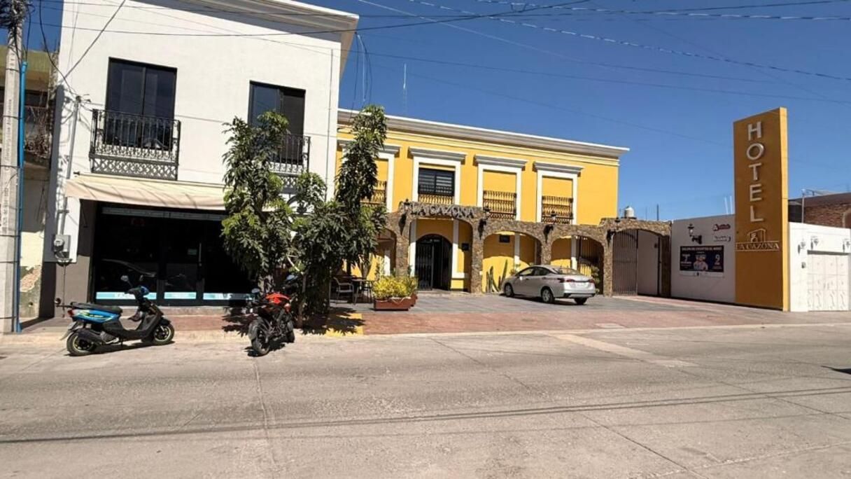 A hotel with a yellow facade, a visible garage, and a parked car.