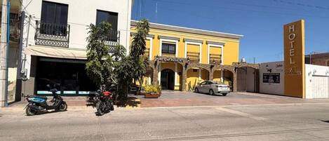 A hotel with a yellow facade, a visible garage, and a parked car.