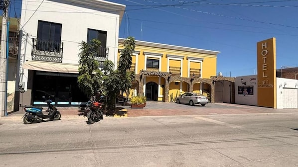 Un hôtel avec une façade jaune, un garage bien visible et une voiture garée.