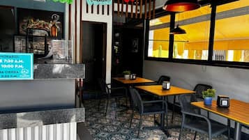 A restaurant interior with a counter, tables, chairs, and a view through a window.