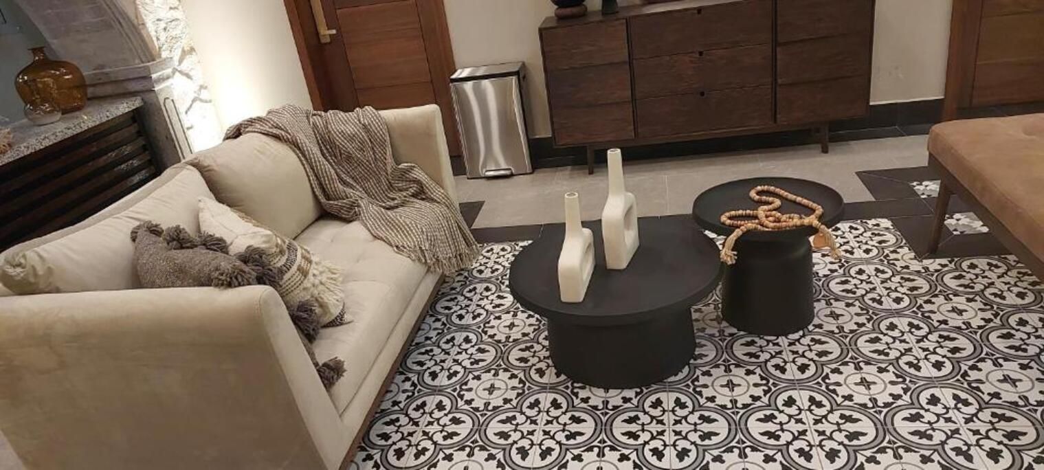 Ein Wohnzimmer mit einer Couch, einem Couchtisch und einem gemusterten Boden.