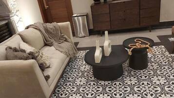 Ein Wohnzimmer mit einer Couch, einem Couchtisch und einem gemusterten Boden.