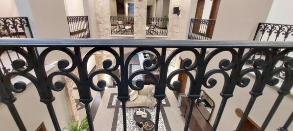 A multi-level interior with a balcony railing, a patterned floor, and a sofa.
