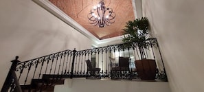 A staircase with ornate black railings and a chandelier.