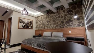 Un dormitorio con pared de piedra, una cama con cabecera de madera, un escritorio y una silla.