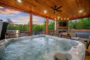 Tinaja con chimenea de piedra, asientos exteriores y vistas a árboles y casas.
