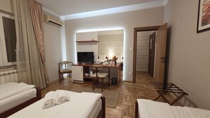 Una habitación de hotel con dos camas, un escritorio con computadora, una silla y un televisor.