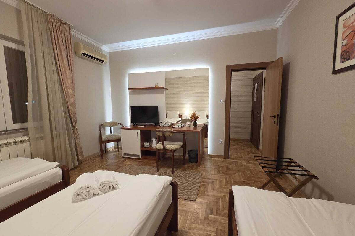 A hotel room with two beds, a desk with a computer, a chair, and a TV.