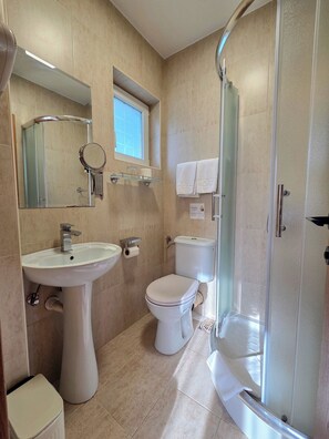 A bathroom with a pedestal sink, toilet, and a glass-enclosed shower. - Vila Forest (Belgrade)