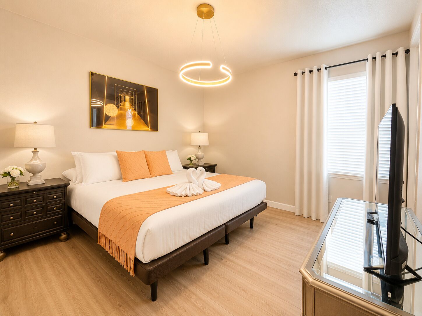 A hotel room with a bed, two bedside tables with lamps, a painting on the wall, a television, and a window with curtains.