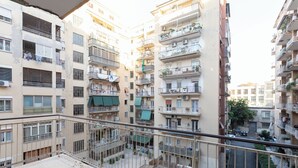 Um edifício residencial com vários andares, varandas, aparelhos de ar condicionado e um pátio murado.