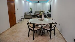 Un comedor con una mesa redonda y sillas, un sofá y un ventilador de techo.