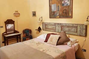 Ein Schlafzimmer mit einem Bett, einem Schreibtisch, einem Stuhl, einer Lampe und einem Bild an der Wand.