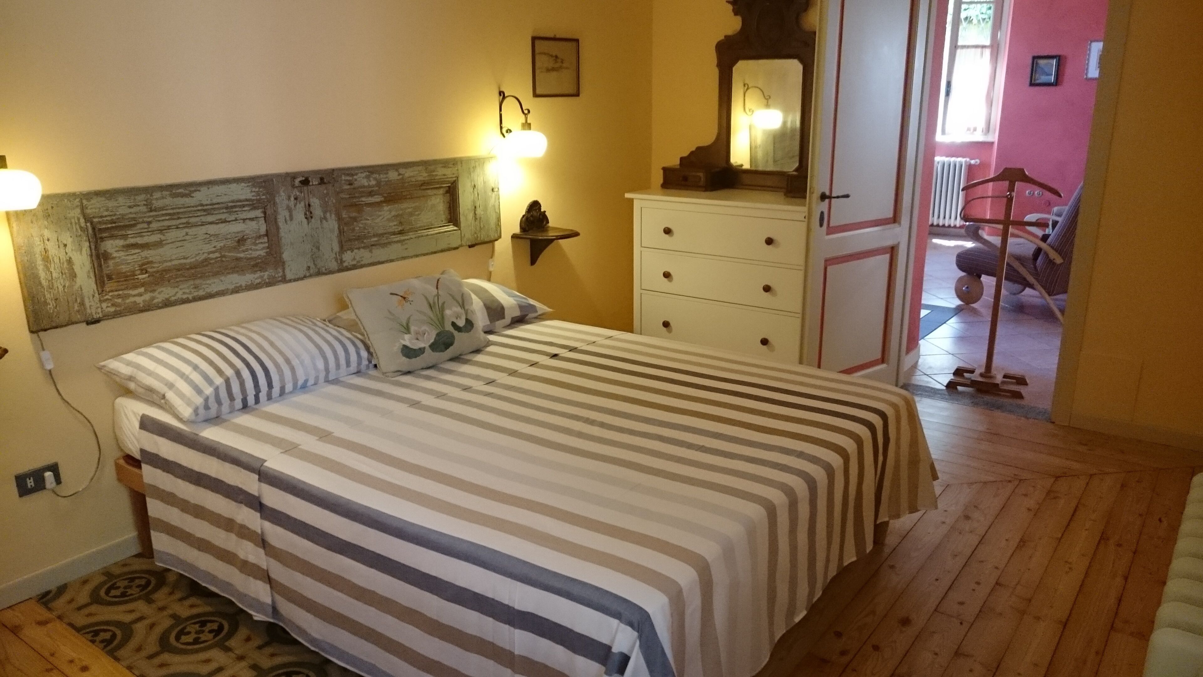 A bedroom with a bed, a dresser, a mirror, and a lamp.
