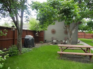 A backyard with a wooden fence, a covered grill, two Adirondack chairs, a birdhouse, and a picnic table. - Moose Traks
Come stay in Downtown Red Lodge, 2 blocks from Broadway Street (Red Lodge)