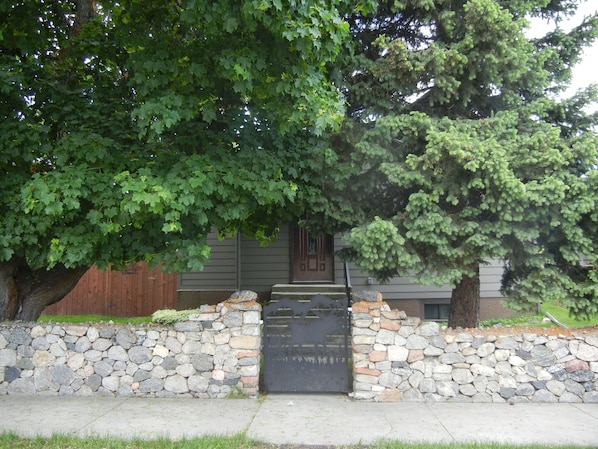 A stone wall with a wooden door, surrounded by lush green trees. - Moose Traks
Come stay in Downtown Red Lodge, 2 blocks from Broadway Street (Red Lodge)