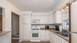 A modern kitchen with white cabinetry, a stainless steel sink, and a microwave.
