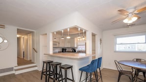 A modern kitchen with a central island, bar stools, and a dining table with chairs.